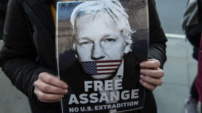 Free Assange. No US Extradition. Cartel sostenido con las manos.
