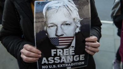 Free Assange. No US Extradition. Cartell sostingut amb les mans. Free Assange. No US Extradition. Cartell sostingut amb les mans.