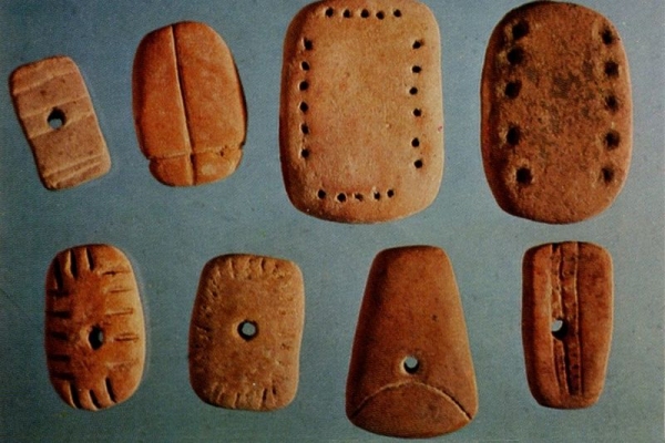 These perforated tokens with incised  rectangles were probably strung together.